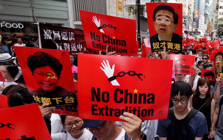 Demonstrators hold signs during a protest to demand authorities scrap a proposed extradition bill with China, in Hong Kong