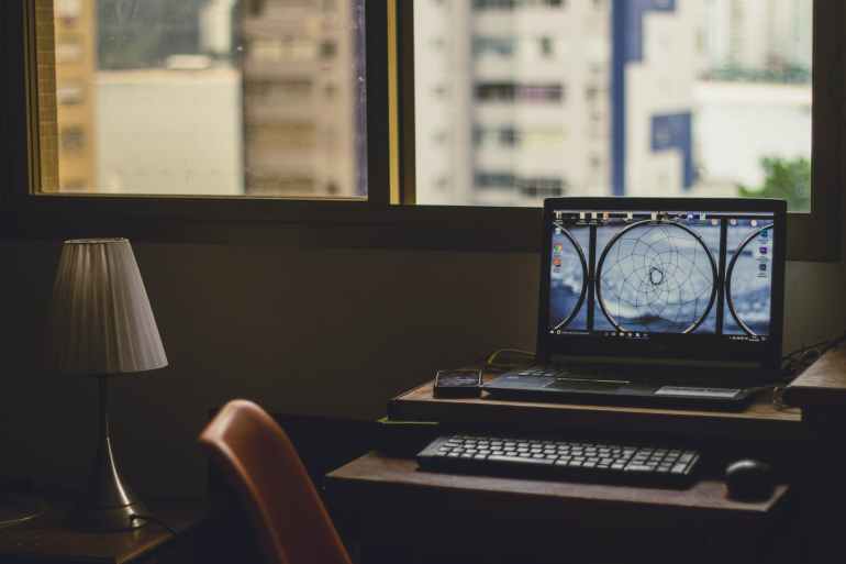 black laptop computer turned on near window at daytime